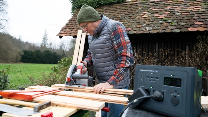 Schneider OffGrid 730 Portable Power Station for Heavy Duty Tools A carpenter using a Schneider OffGrid 730 portable power station to run an electric saw outdoors